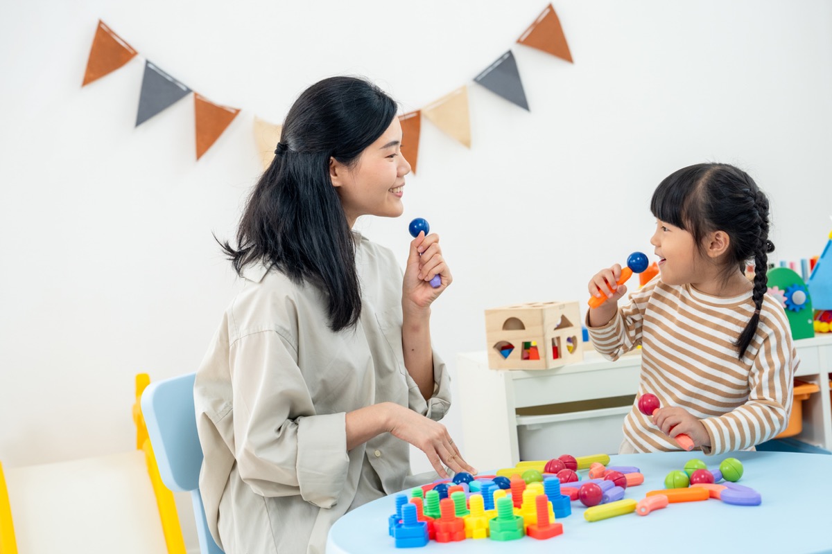 華人媽媽和幼兒一起拿著玩具麥克風，在家互動遊戲